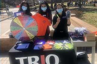 Three TRiO volunteers showing off TRiO merchandise.